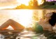 A woman in a green bikini laying in the water.