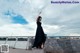 A woman in a black dress standing on a stone wall.