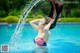 A woman in a red, white and blue bikini splashing water on her head.