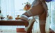 A woman in white stockings and high heels sitting on a table.