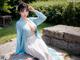 A woman in a blue and white dress sitting on a stone wall.