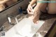 A woman is washing her feet in a bathroom sink.