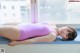 A woman in a pink bathing suit laying on a window sill.