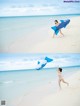 A woman in a bikini running on the beach with an inflatable shark.